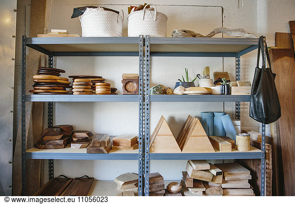 Regale in einer Drechslerwerkstatt und eine Ausstellung glatter Holzklötze und runder Teller und Schalen.
