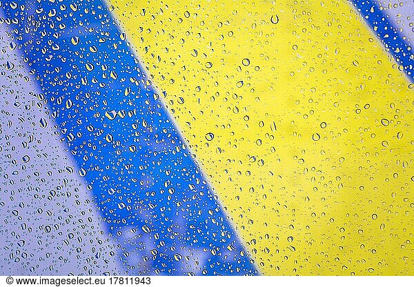Regentropfen mit ukrainischen Flagge Hintergrund  Regentropfen auf Glas mit Farben der ukrainischen Flagge. Regentropfen auf Fenster auf Glas Hintergrund