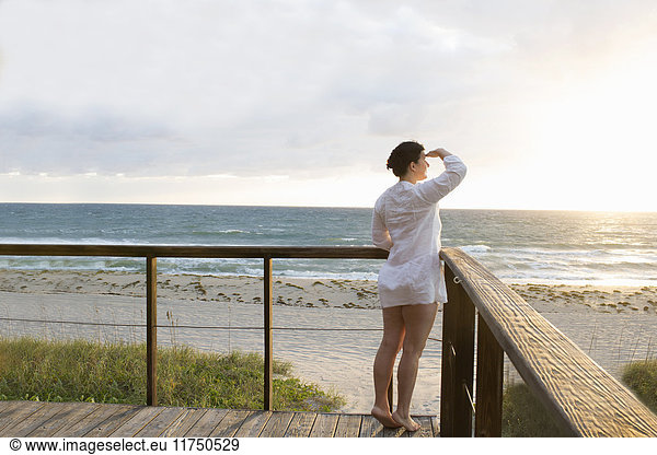 Reife Frau auf Balkon  die die Augen vor Sonnenaufgang über dem Meer schützt  Spanish River Park  Boca Raton  Florida  USA