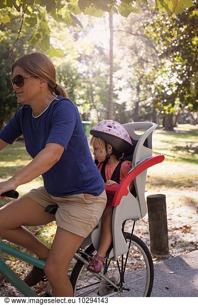 Reife Frau auf dem Fahrrad mit Tochter auf dem Kindersitz hinter ihr