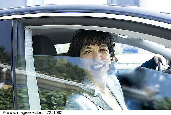 Reife Geschäftsfrau lächelt beim Blick durch das Autofenster