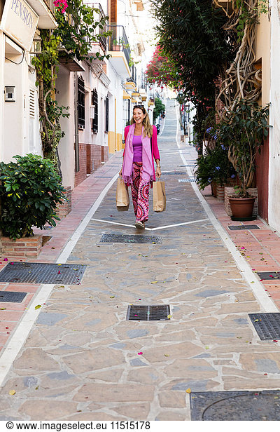 Reife Touristin schlendert mit Einkaufstaschen durch eine Gasse  Marbella  Spanien