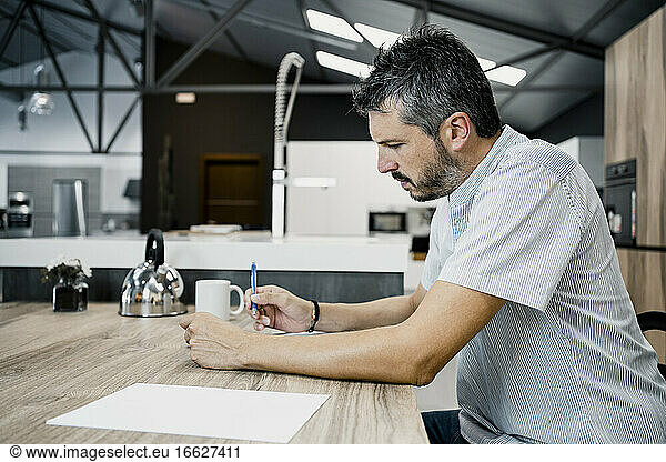 Reifer männlicher Freiberufler  der am Schreibtisch im Büro sitzt
