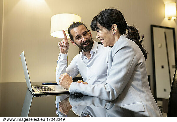 Reifes Paar in Geschäftskleidung diskutiert vor einem Laptop in einer Hotelsuite