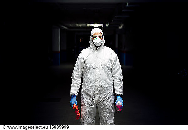 Reinigungspersonal im Anzug mit Desinfektionsmittel und Reinigungstuch