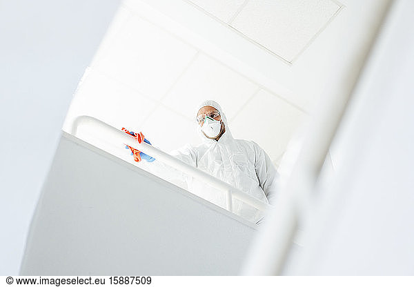 Reinigungspersonal im Anzug reinigt Geländer mit Desinfektionsmittel