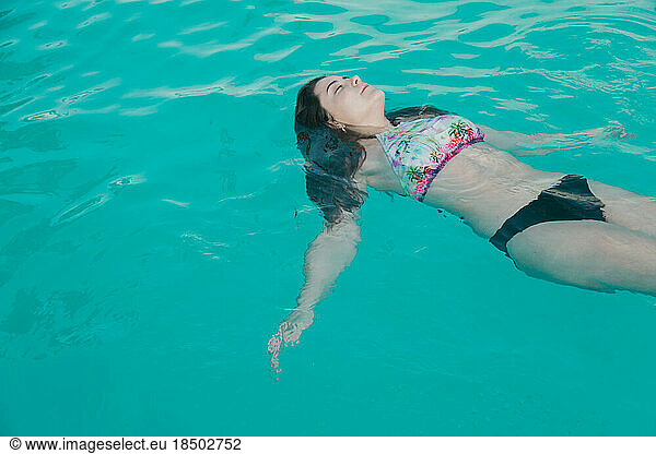 Relaxed girl with swimsuit lying in the pool water