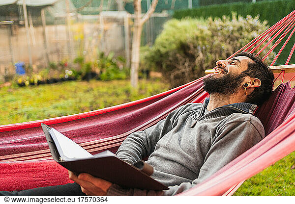 relaxed hipster man in hammock reading a book