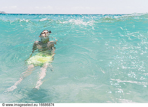 relaxed white boy with closed eyes diving a wave in the sea in summer