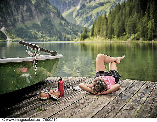 Relaxed woman lying down on jetty by lake