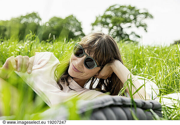Relaxed woman lying on a meadow reading a book