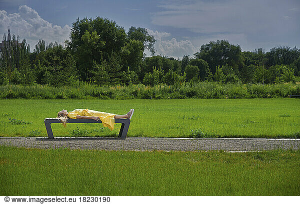 Relaxed woman lying on bench at park