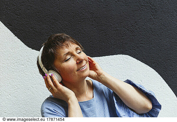 Relaxed woman with closed eyes listening music with headphones