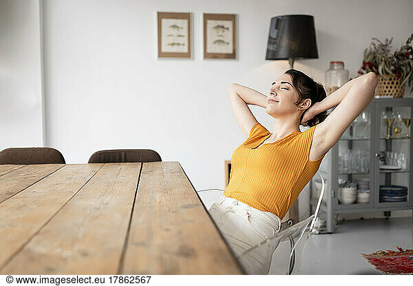 Relaxing woman sitting at dining table at home relaxing
