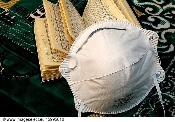Religion and coronavirus ( COVID-19). Quran and disposable surgical mask.