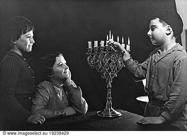 Religion / Jewish Religion. Children lighting a Hanukkah Menorah (Germany). Photo  1930s  by Arno Kikoler.