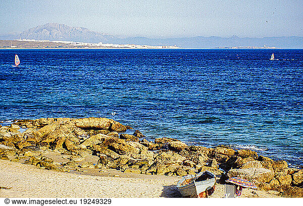 Report Illegal migration from Morocco to Spain. People from Africa are trying to get to the territory of the European Community (today: European Union) for a variety of reasons. A large proportion of immigrants attempt the sea route from Morocco to Spain  using small keelless wooden boats ( pateras ) with outboard motors. Some also try to hide on ferries from Morocco to Algeciras (Spain).
Here: Tourist on the beach of Tarifa. Next to it a wooden boat abandoned by illegal immigrants.
Tarifa (Spain)  1993.