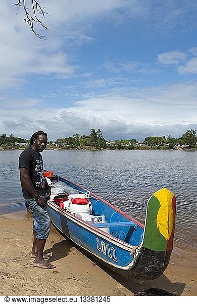 Republic of Suriname  Lawa River becoming downstream the Maroni River  pirogue in charge and stranded on the shore side Suriname  portrait of a boatman (Seke)  in the background the village of Grand-Santi