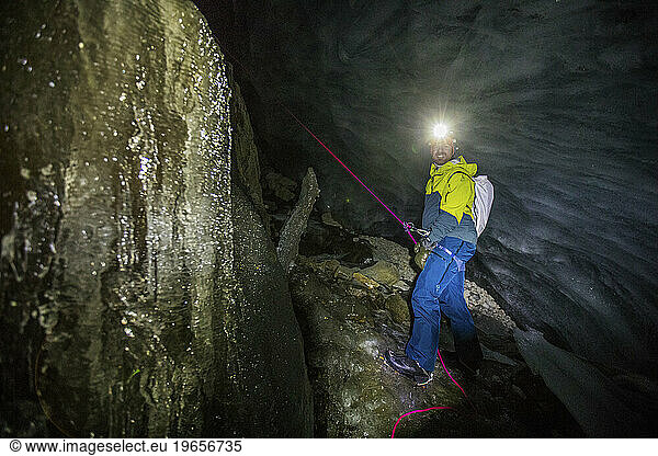 Rescuer shines headlamp inside glacial crevasse  searching