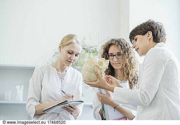 Researcher explaining over human skull to colleagues in laboratory