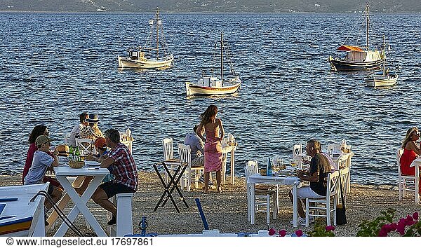 Restaurant-Tische  direkt am Strand  Fischerboote  Abendlicht  Touristen  Klima  Golf von Milos  Insel Milos  Kykladen  Griechenland  Europa