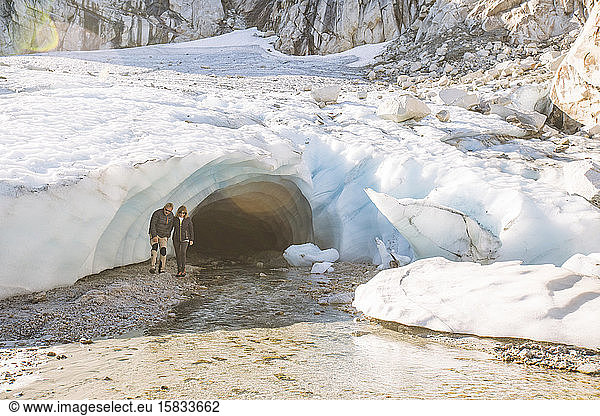 Retired couple emerge from glacial ice cave during luxury tour.