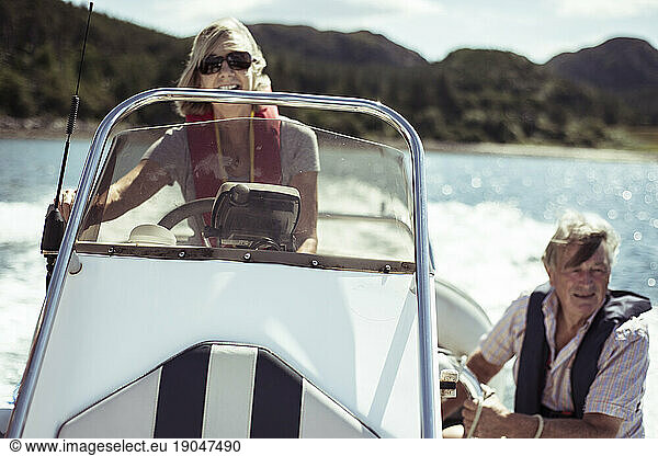 Retired couple laugh on speed boat in the sun