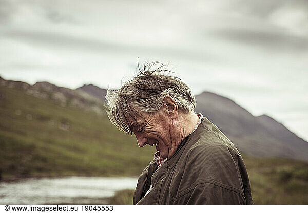 retired man laughs and smiles out fishing in remote river mountian