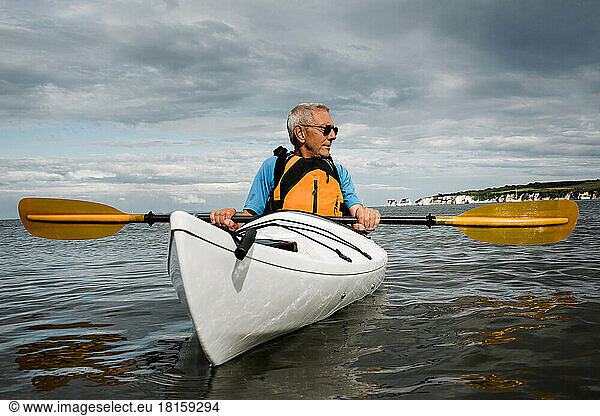 retired man out exercising in the sea on a kayak in the Jurassic Coast