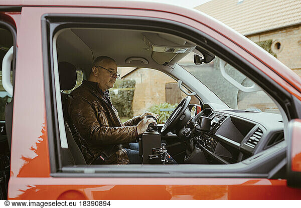 Retired senior man with disability sitting inside van