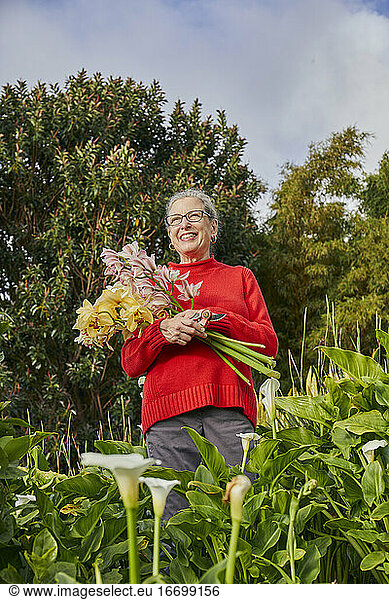 Retired Woman Holding Freshcut Flowers in her Garden