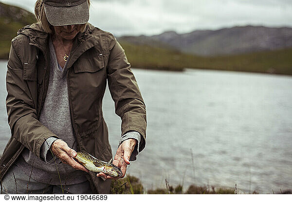 retired woman holds wild trout from caught from loch in scotland