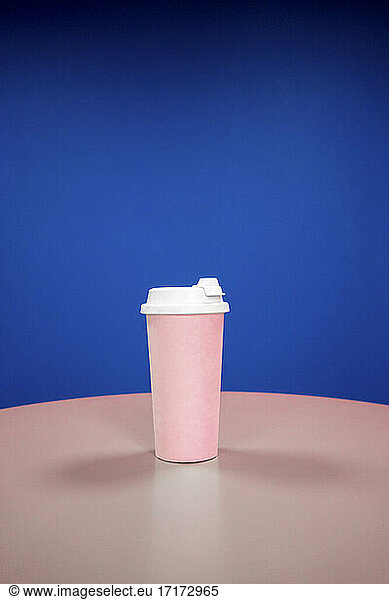 Reusable coffee cup on table against blue background