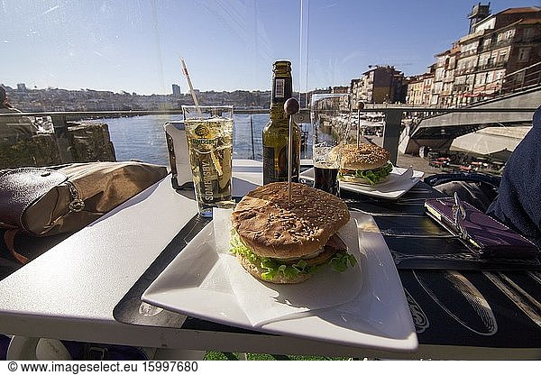 Ribera district is World Heritage site in Porto on January 7  2017 Portugal. Eating burgers over the Douro river under the Luis I bridge.
