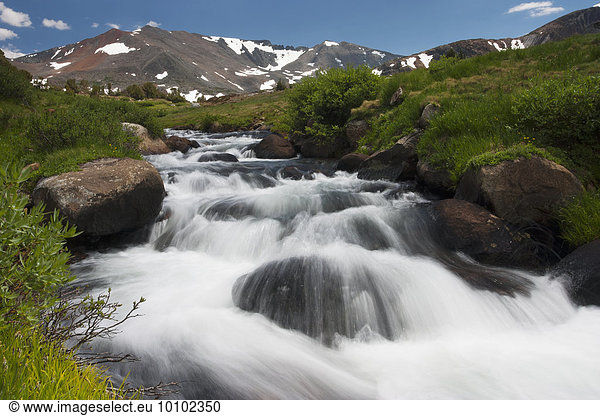 River flowing through a landscape with snow-capped mountains in the distance in California.