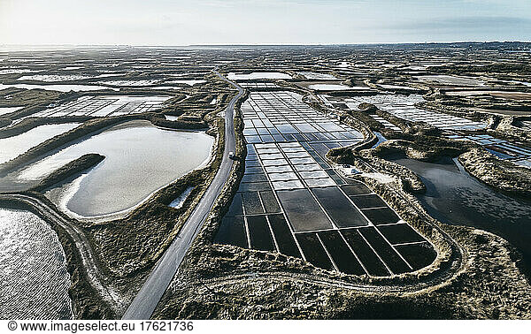 Road amidst salt pans on sunny day