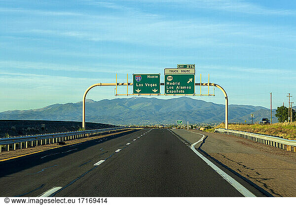 Road sign on highway against blue sky