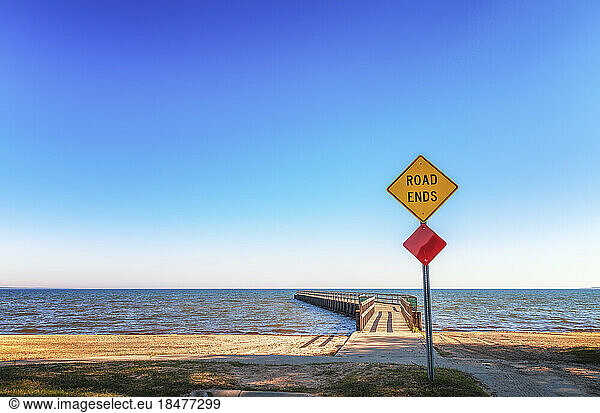 Road sign with Road Ends text in front of pier  Lake Huron  Michigan  USA