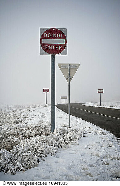 Road signs on road in wintry landscape.