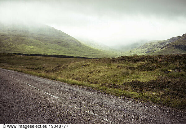 Road through misty mountains in scottish highlands