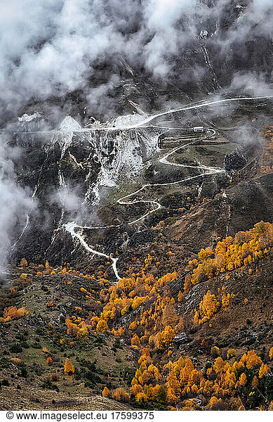 Road winding across mountainous landscape of North Caucasus on foggy autumn day