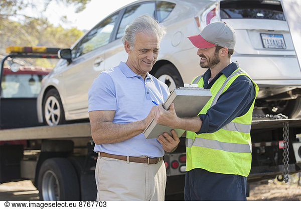 Roadside mechanic and man with paperwork