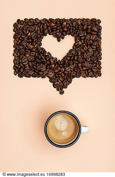 Roasted coffee beans arranged into shape of heart inside online chat bubble
