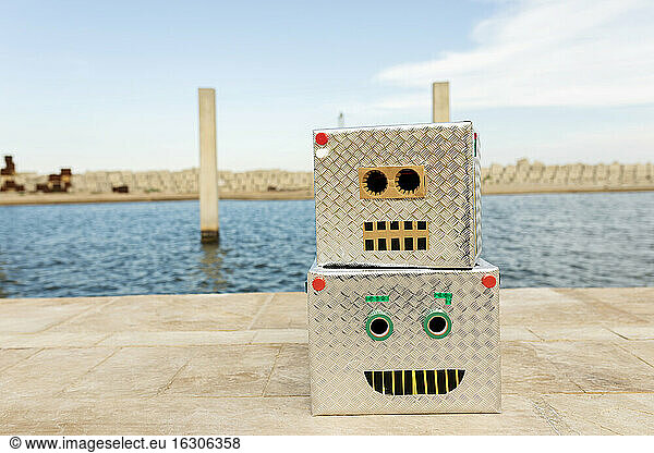 Robotermasken aus Kisten auf dem Fußweg gegen Wasser