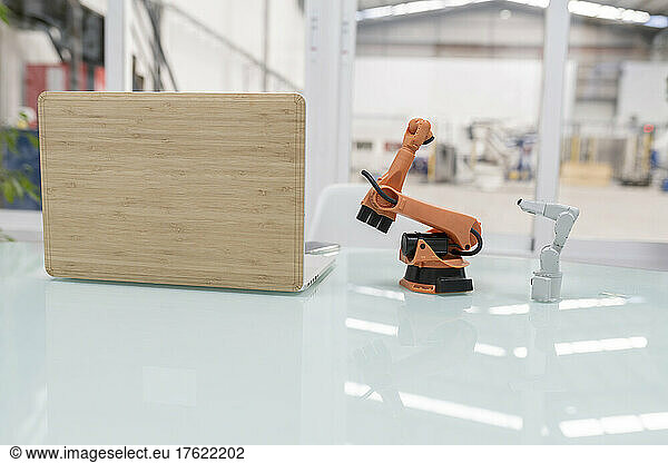 Robotic arm model by laptop on desk in factory