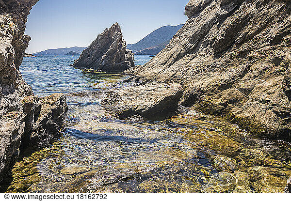 Rock formation in sea on sunny day