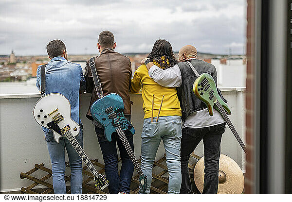 Rock musicians standing together with electric guitars on rooftop