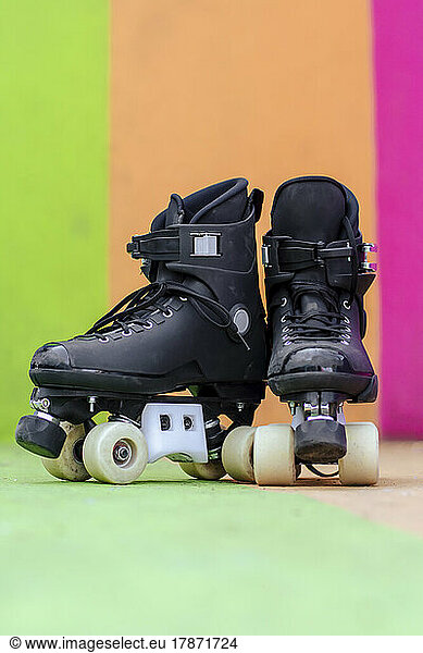 Roller skates on floor in front of multi colored wall