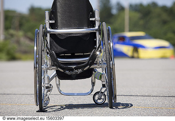 Rollstuhl und Rennwagen im Hintergrund