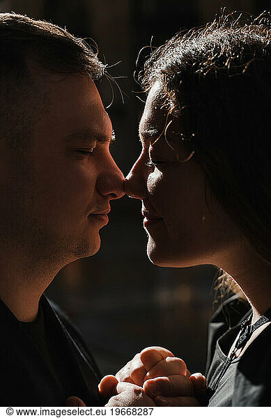 Romantic close-up portrait of lovers in black clothes  back light